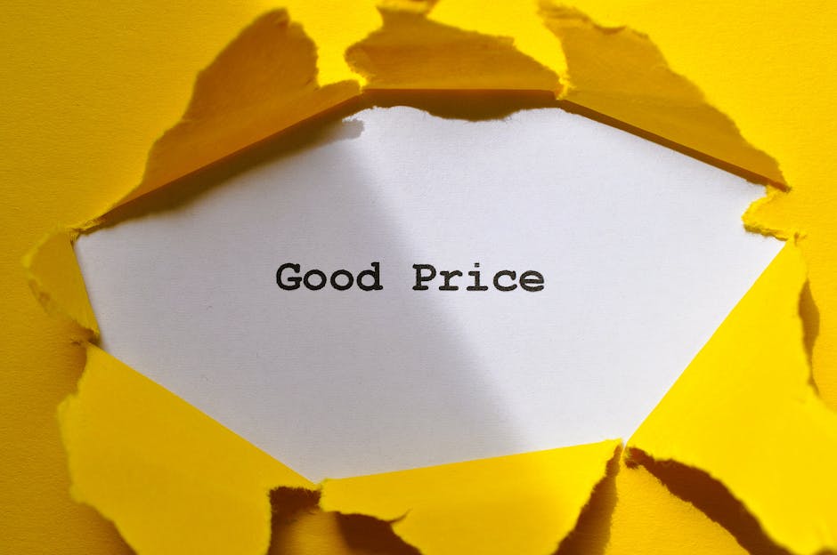 A close-up image showing a square hole torn through a bright yellow paper, revealing a white sheet of paper underneath with the phrase 'Good Price' printed in black text. The torn edges of the yellow paper are rough and irregular, suggesting an intentional ripping to expose the message. The background around the tear matches the yellow paper, creating a stark contrast that emphasizes the printed message. This visual is associated with the theme of transparently understanding removals pricing, as seen on the webpage for Man With a Van Mitcham, with contextual relevance to home relocation, packing, and furniture transport processes involved in house removals.