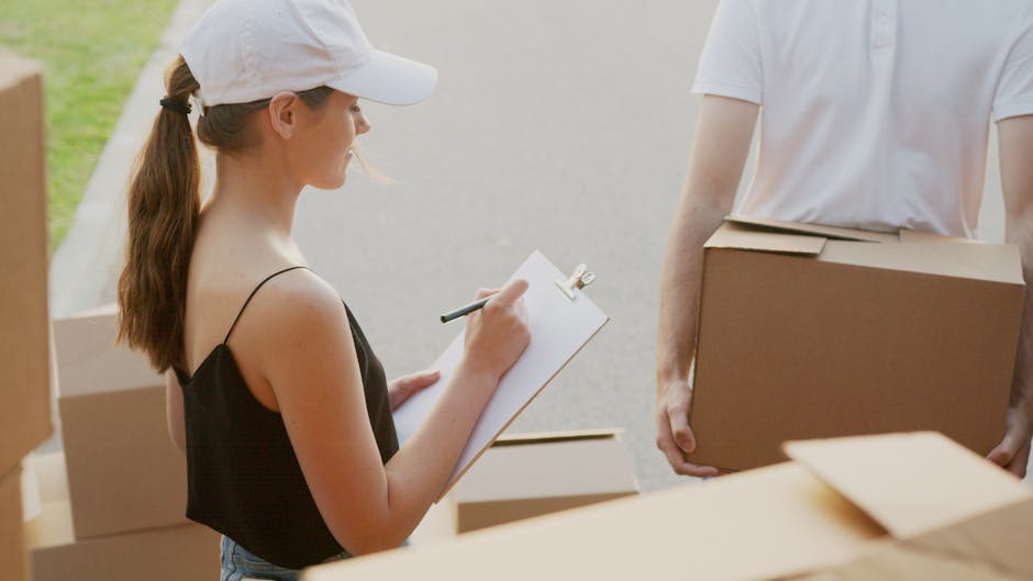 A woman wearing a white cap and a black sleeveless top is using a clipboard and pen to take notes during a home relocation process. She is standing outdoors near the entrance of a property, with sever